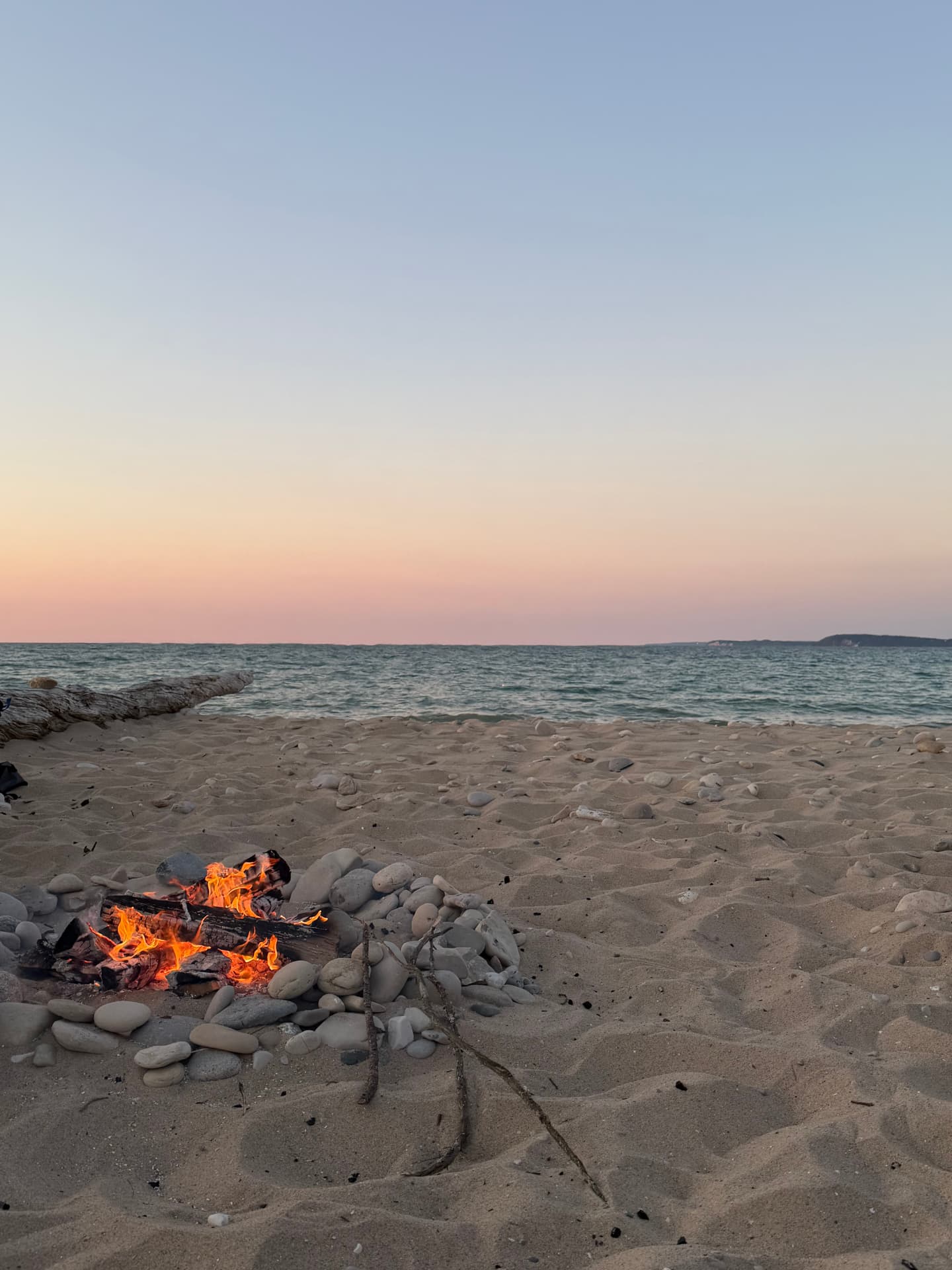 A small campfire on a pebbled Lake Michigan shoreline at sunset. Photograph by Matt Schertzer.